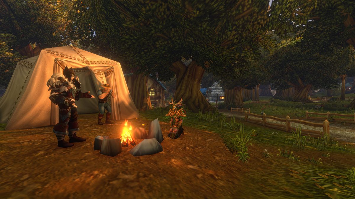 Players gathered around a campfire beside a tent at dusk